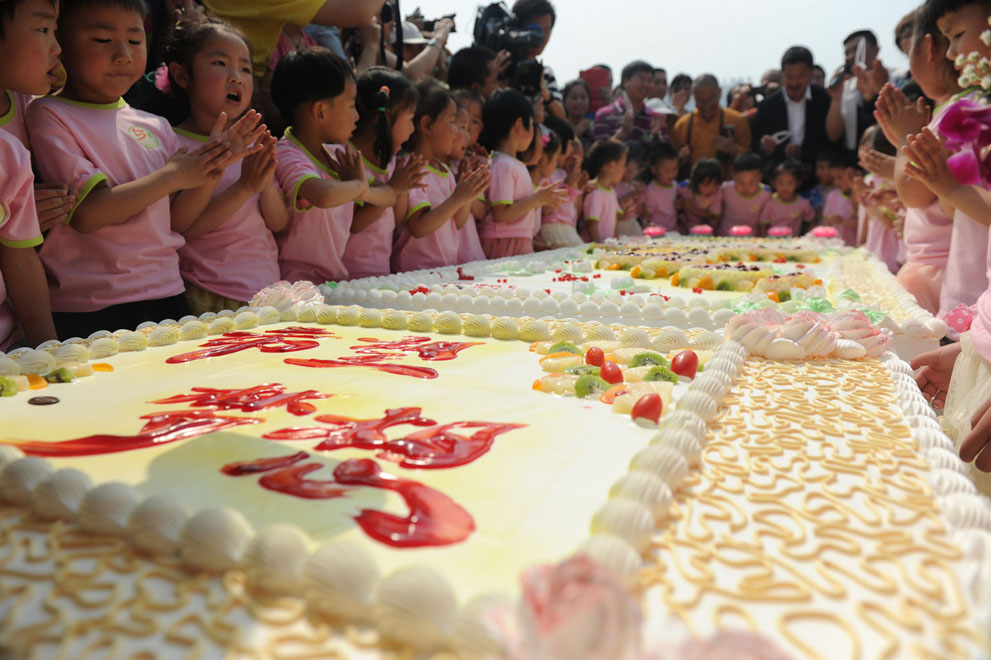 Дети собрались вокруг пирога во время празднования своих дней рождения в храме в Шифане, провинция Сычуань, 12 мая 2013
