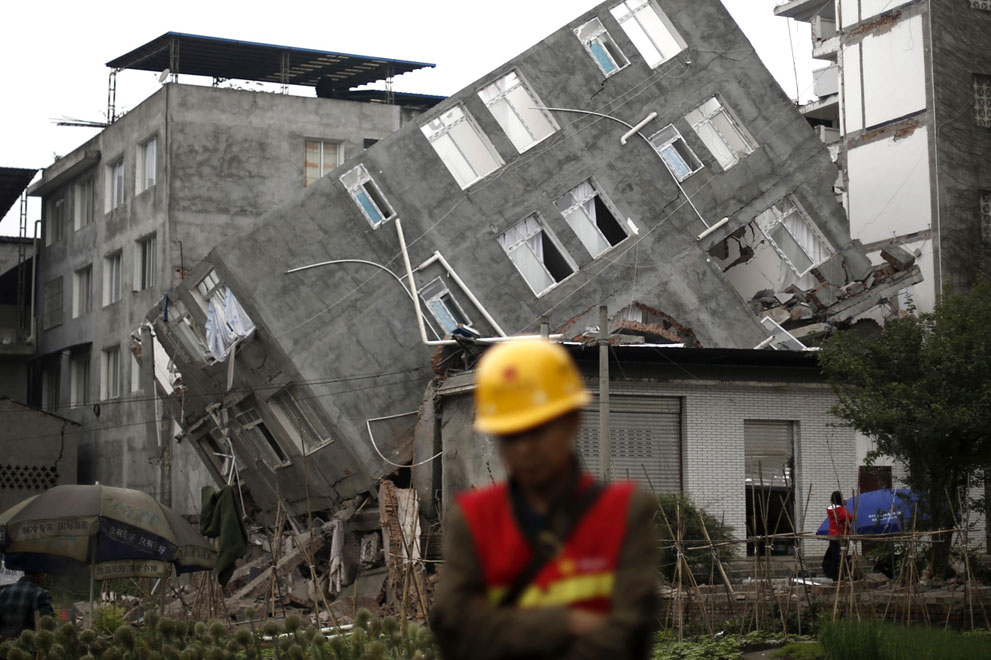 Спасатель идет мимо разрушенного здания после субботнего землетрясения в Лингуане, уезд Баосинь, провинция Сычуань, Китай, 22 апреля 2013