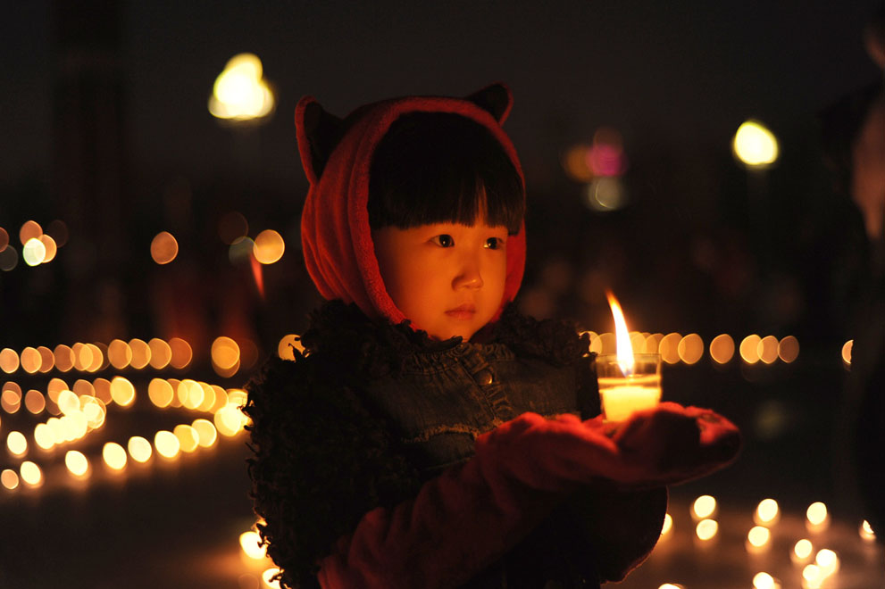 Девочка держит свечу во время молитвы за пострадавших от землетрясения в Дацине, северо-восточная китайская провинция Хэйлунцзян