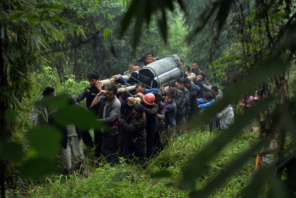Люди несут гроб с телом жертвы землетрясения в Лушане
